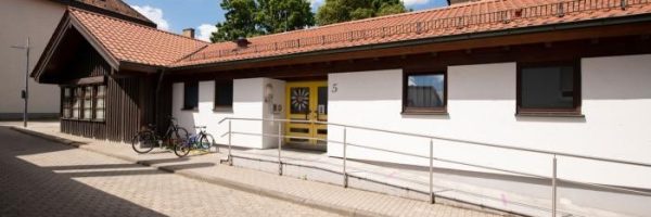 Eine einstöckige Kindertageseinrichtung am Klostergraben mit rotem Ziegeldach und weißen Wänden.