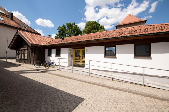 Eine einstöckige Kindertageseinrichtung am Klostergraben mit rotem Ziegeldach und weißen Wänden.